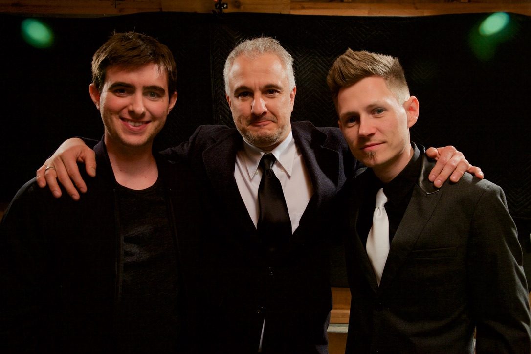 Reid, Peter Boghossian and Buck Bowen with their arms around each other on a dark set